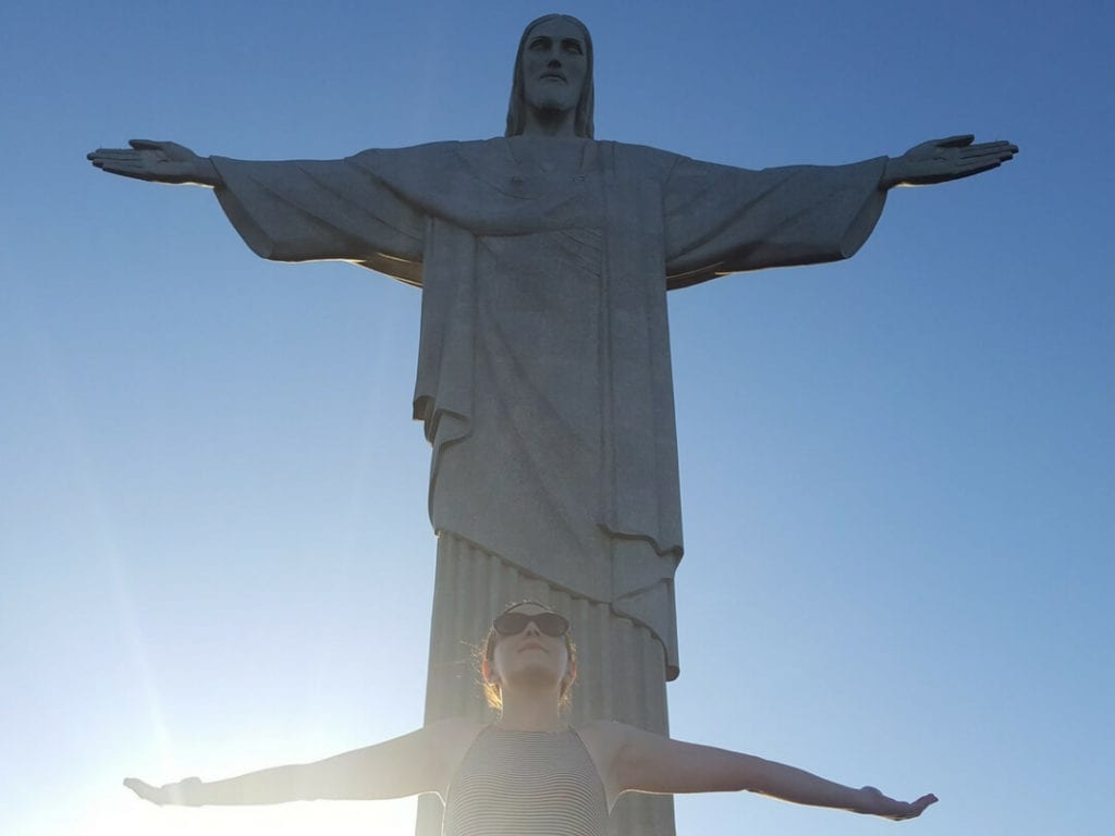 A photo of a woman posing with Christ the Redeemer which is one of the interesting things to do in Rio