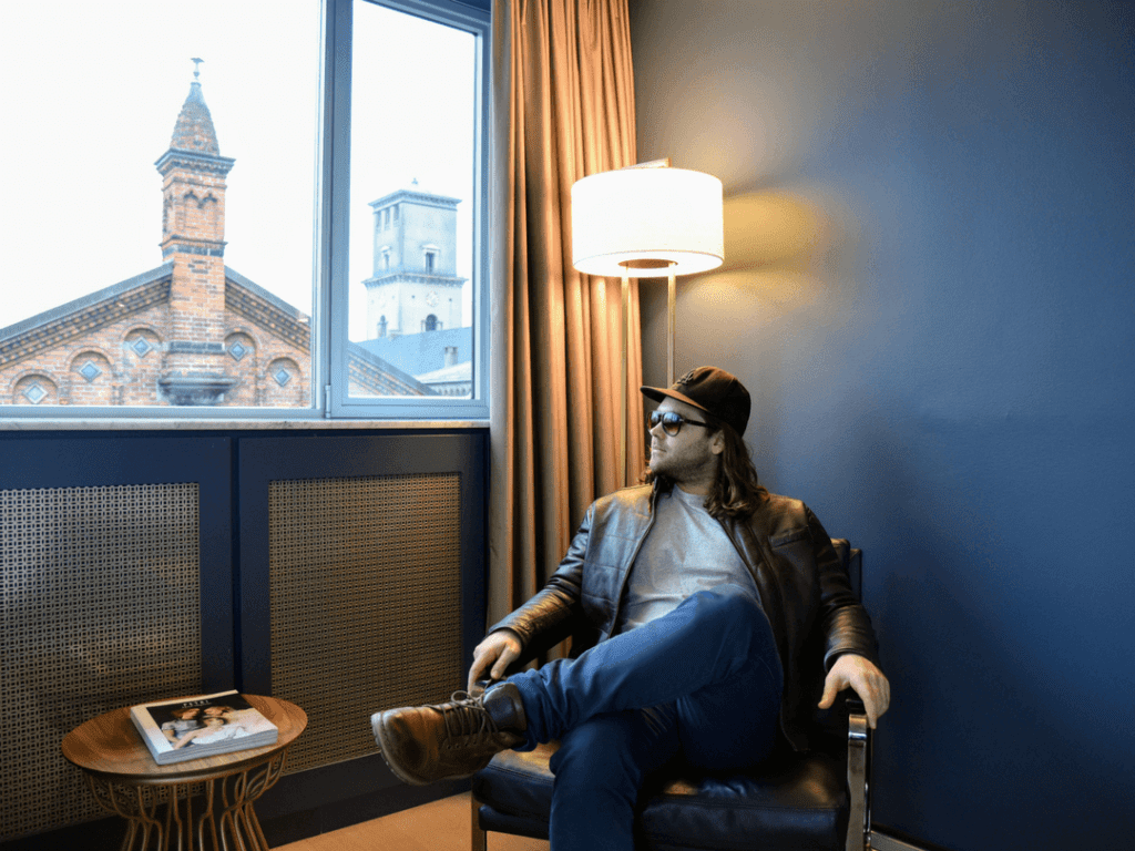 A photo of a man relaxing in the Deluxe Room of Skt Petri Hotel, one of the best 5 star hotels in Copenhagen