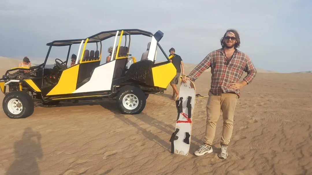 man-standing-with-sandboard-on-huacachina-tour