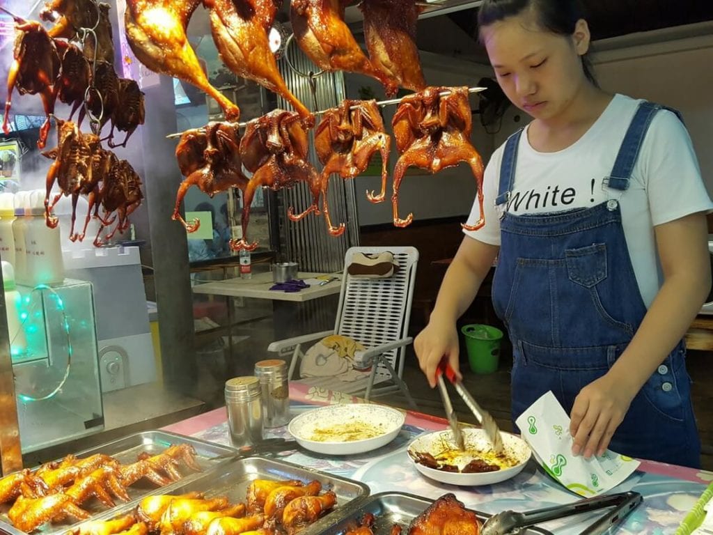A photo of a Chinese girl preparing duck in Guilin, food in guilin, guilin xicheng pedestrian street, best food in guilin