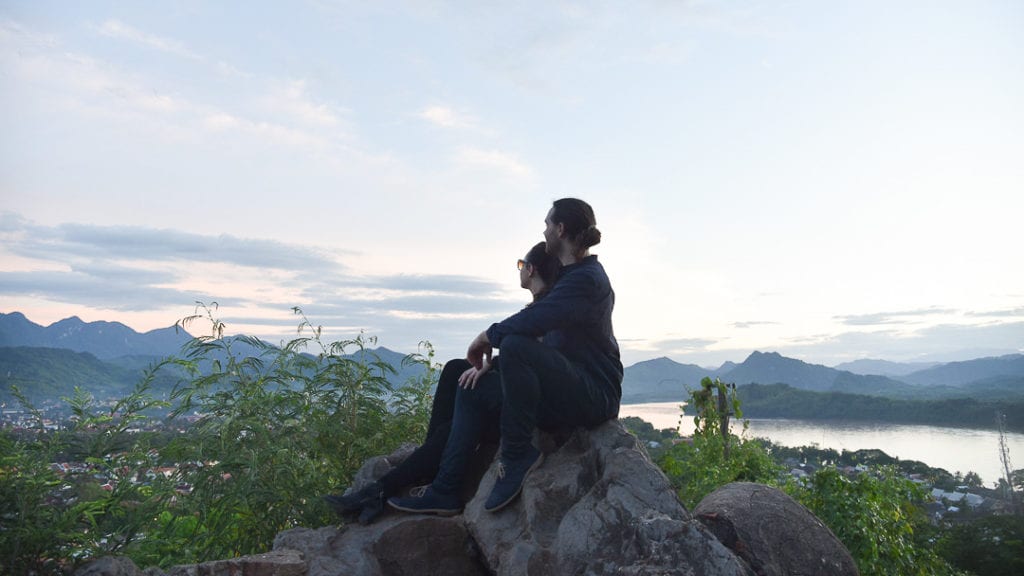 A travel couple watching sunset at Mount Phousi, Laos