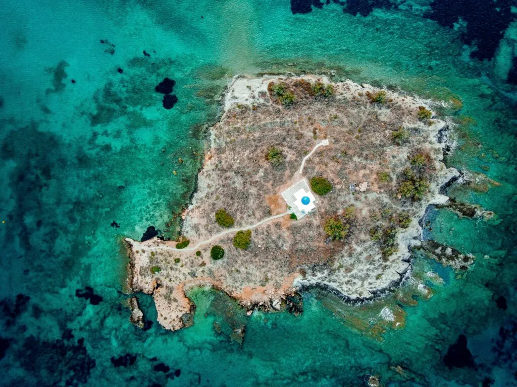 Island with tiny white church taken by drone on Paros